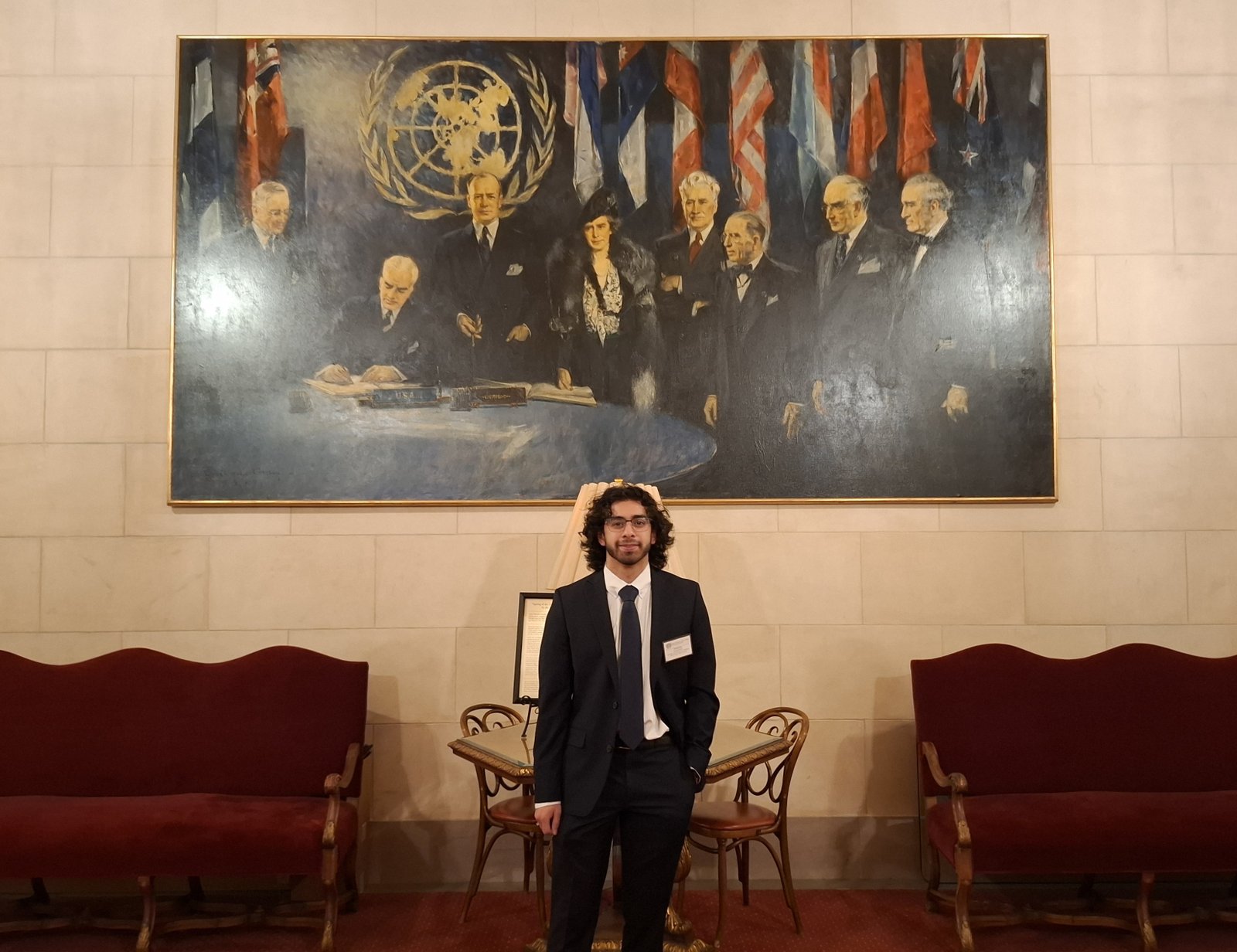 Hamed Emari standing in front of the UN founding mural